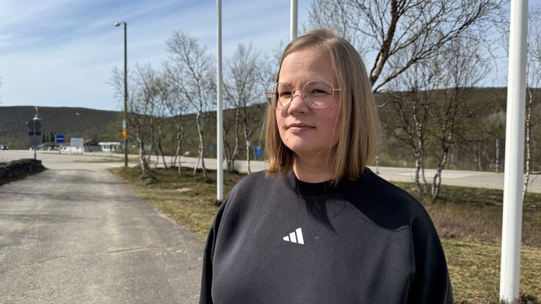 Kaisa Tapiola katsoo totisena kameraan taustanaan Utsjoen kyläraitti.