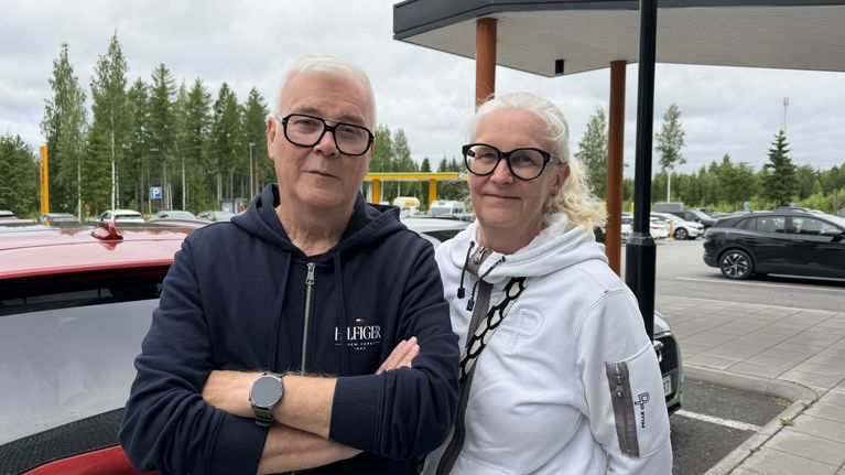 Mies ja nainen seisovat parkkipaikalla.