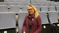 Nainen istuu tyhjässä teatterin katsomossa etuosassa, takana nouseva katsomo.