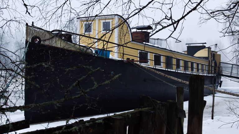 Vaaleankeltainen asuntoproomu Kaunis Veera Porvoossa sumuisena päivänä.