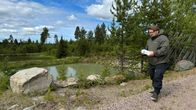 Mies kävelee muovinen näytepullo kädessä kaivosalueella.