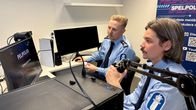 Kaksi poliisia istuu tuolilla ja katsovat pelinäyttöä. Näytöllä lukee teksti pelipoliisi.