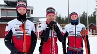 Kolme hiihtäjää seisoo hiihtoladun reunalla sauvat käsissään.