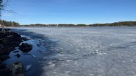 Keväistä järven jäätä, joka on rannasta jo sulanut. Rannassa isoja kiviä.