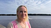 Finance Minister Riikka Purra posing for the camera. She is standing in front of a lake.