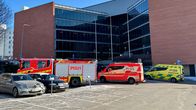 Pelastusyksiköt, mukaan lukien palo- ja ambulanssiautot, ovat saapuneet paikalle hoitamaan hälytystehtävää modernin rakennuksen edustalla.
