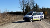 Poliisiauto poikittain hiekkatiellä, taustalla näkyy rakennuksia.
