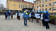 Ihmisiä kylttien kanssa osoittamassa mieltä Jyväskylän ammattikorkeakoulun pihamaalla.
