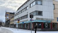Autio, valkoinen kolmikerroksinen talo. Tyhjä liiketila alakerroksessa.