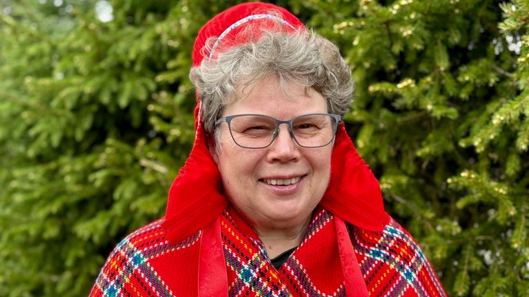 Nainen seisoo ulkona saamenlakki ja villahuivi päällä. Henkilökuva. Maire Saijets.
