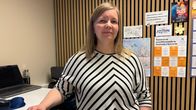 Näinen seisoo toimistossa ja on pukeutunut raidalliseen puseroon.
