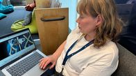 Nainen esittelee tietokoneelta saamenkielistä sivustoa. 