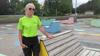 En kvinna som står vid ett torg med färgglada solstolar i trä.