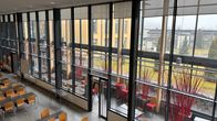En modern och ljus lokal med fönster från golv till tak och färgglada sittplatser. Vinterträdgården i YH Novia i Ekenäs.