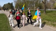 Barn och vuxna som går i en parad med den ukrainska flaggan.