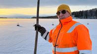 Oranssitakkinen Janne Kuivalainen seisomassa jäätyneen järven edessä.