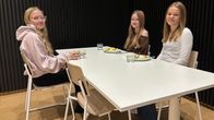 Kolme koululaista istuu ruokapäydän ääressä ja heillä on ruokaa lautasilla.