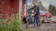 Mies hymyilee kameralle piettäessään pyörän tangosta kiinni.