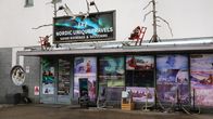 Turisteille Lapissa tarjoavan yrityksen toimipisteen julkisivu, jonka ikkunat on teipattu täyteen mainoksia, etualalla kaksi ulkoständiä.