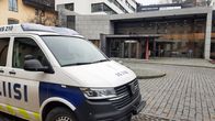 En polisbil står parkerad på en stenlagd innergård vid ett hus med glasväggar. Ovanför ingången står Turun oikeustalo Åbo rättscenter.