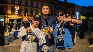 Kolme Suomen pelipaitoihin pukeutunutta nuorta miestä poseeraa kameralle. Yhden miehen paidassa on pelaajien nimikirjoituksia.