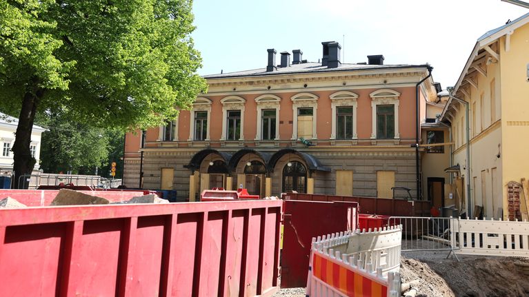 Containrar och staket framför en gammal byggnad.