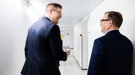 Politikerna Lindtman och Orpo går bredvid varandra i en korridor, båda skrattar. 
