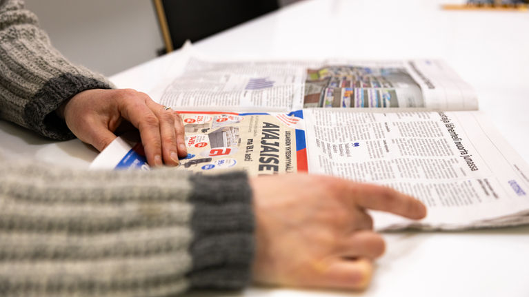 A close up photo of Aamulehti newspaper, with a hand opening a page in the corner.
