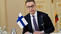 Presidentti Alexander Stubb edessään pieni Suomen lippu.