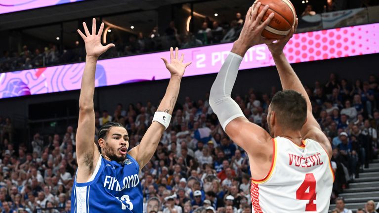 Nikola Vucevic yrittää syöttää koripallon, Olivier Nkamhoua estelee kädet ylhäällä.