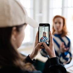 Toimittaja ottaa videoi puhelimella toisesta toimittajaa.