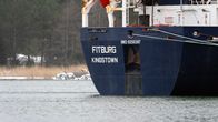 The stern of a large freighter ship, blue on hull and white on deck. The words Fitburg Kingstown in large white letters are seen on the stern.