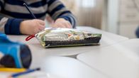Anonyymi oppilas värittää kuvaa oppitunnilla penaalin ollessa etualalla.