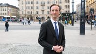 Ilmari Nurminen pukeutuneena pukuuun seisoo kaupungin keskustassa.