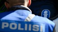 Poliisi-selkätunnuksella varustettu henkilö katsomassa auton tavaratilaa, jossa poliisin logolla varustettu laukku.