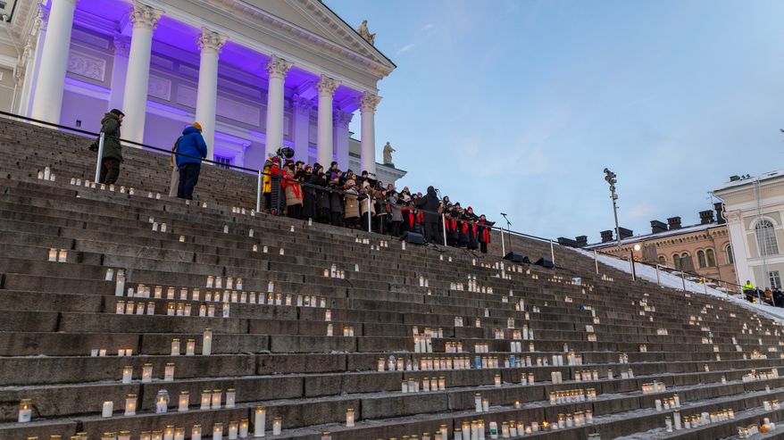 Helsingin tuomiokirkon portailla on laulukuoro ja sen edessä portailla paljon kynttilöitä.