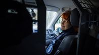 Auton kyydissä istuva poliisi katsoo takapenkille.