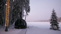Lasi-iglu ja puita lumisen lammen rannalla.