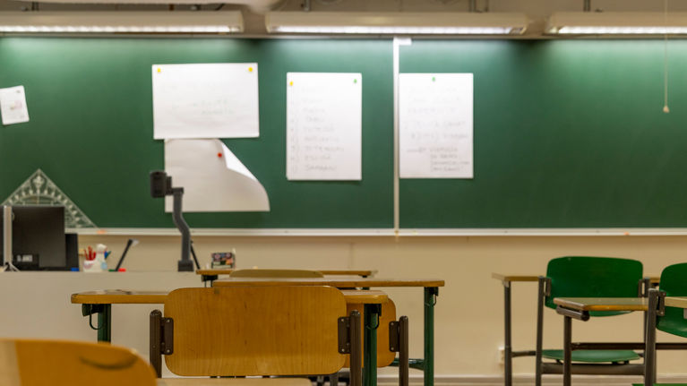 An empty classroom with desks and a blackboard.