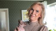 Henkilö pitelee sylissään karvatonta sfinksi-kissaa kodikkaassa ympäristössä.