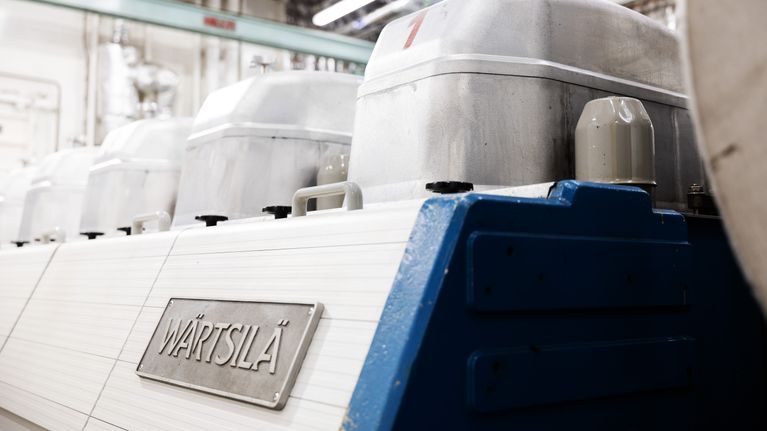 En stor maskindel märkt med texten "WÄRTSILÄ" står inomhus i en industriell miljö.
