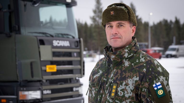 Mies sotilaspuvussa Scanian edessä.