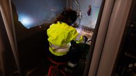 En person i gul varseljacka svetsar vid en arbetsstation omgiven av gnistor.