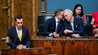 Rydman puhuu, taustalla Orpo ja Adlercreutz kuiskivat.