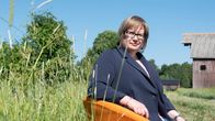 Ympäristöministeriön erityisasiantuntija Maaret Väänänen istuu oranssilla tuolilla keskellä vehreää peltomaisemaa.