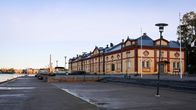 Strandlinje och avlång byggnad i nyrenässans-stil.