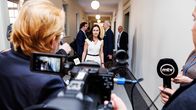 Sanna Marin wearing a white outfit behind a scrum of photographers and journalists.