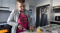 Työtön ravintolatyöntekijä Päivi Ellaniemi leikkaa tuorekurkkua kotinsa keittiössä.