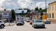 Busy car traffic on a street in a small city with old, low buildings and a cloudy sky.