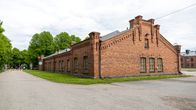 Vanha punatiilinen rakennus seisoo rauhallisella alueella kesäisenä päivänä.